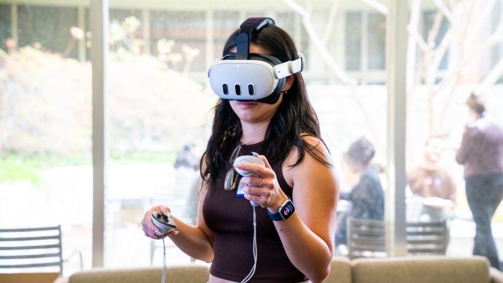 Student wears an Meta VR headset while exploring a virtual world in the Health Equity Lab.