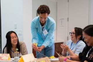 Instructors construct mobiles together at a table.