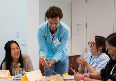 Instructors construct mobiles together at a table.