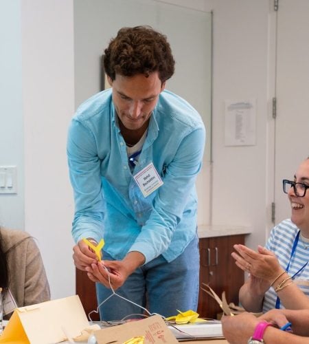 Instructors construct mobiles together at a table.