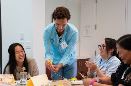 Instructors construct mobiles together at a table.