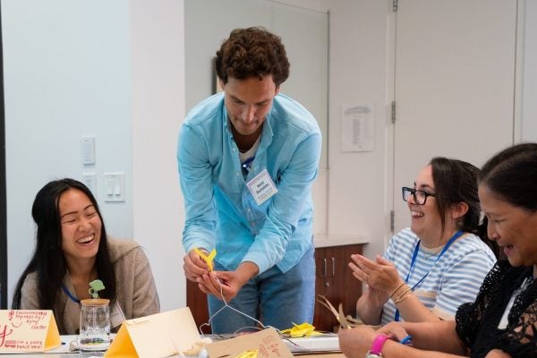 Instructors construct mobiles together at a table.