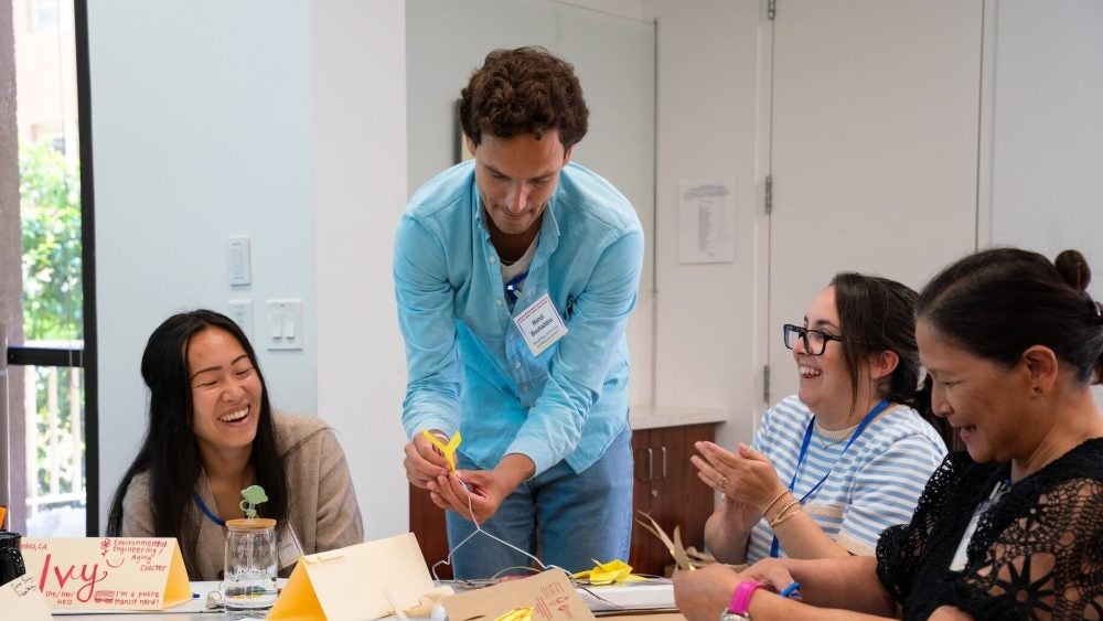 Instructors construct mobiles together at a table.
