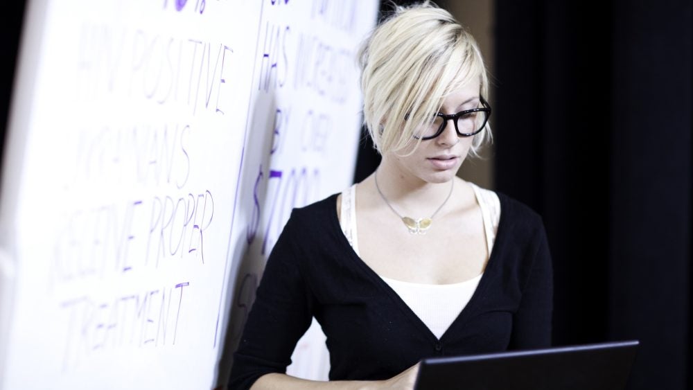 Photo of student with a laptop near a whiteboard