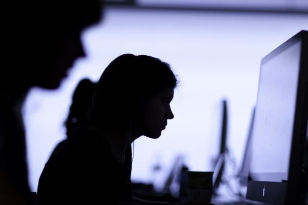 Students working at large computer monitors Working on computers.