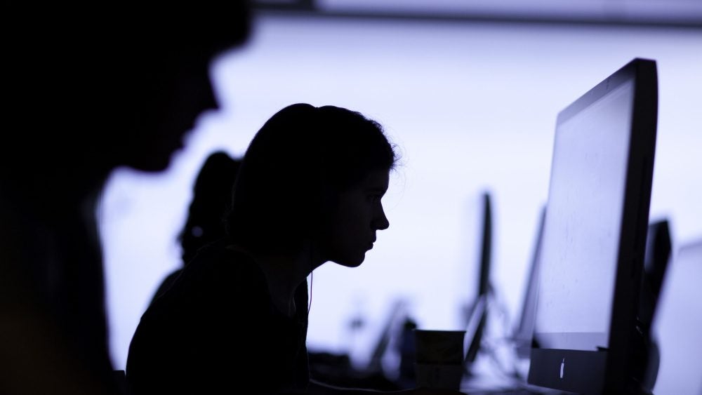 Students working at large computer monitors Working on computers.