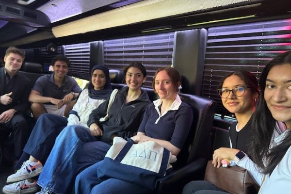 Students seated in the interior of a bus smiling at the camera