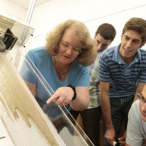 Photo of a class studying the flow of non-toxic liquids combined with glass beads to simulate the dynamics of the movement of oil that has saturated beach sand.