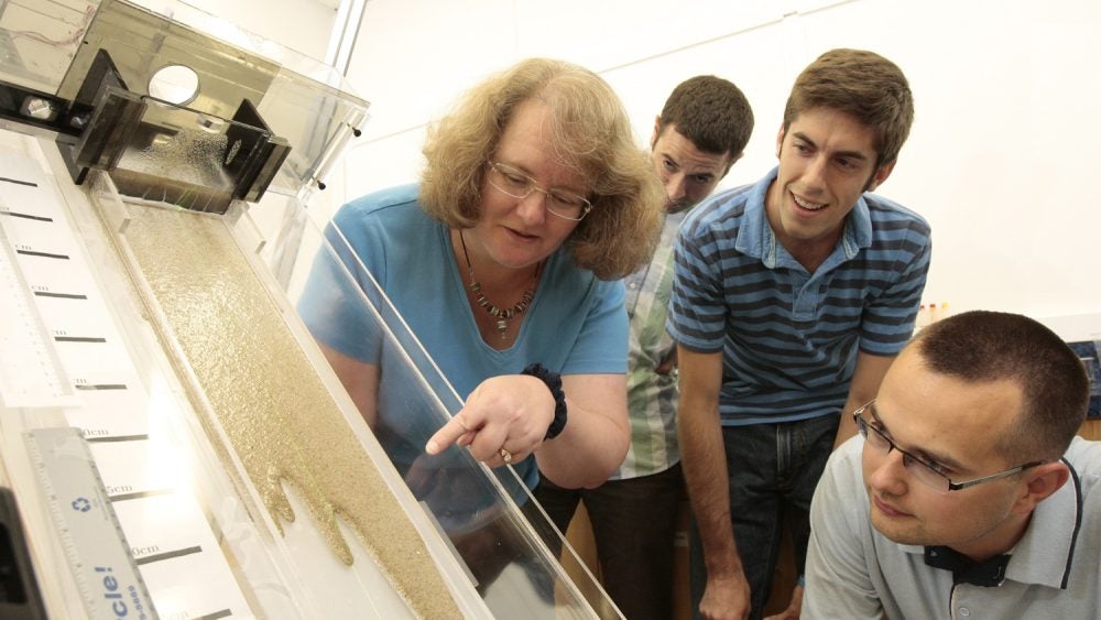 Photo of a class studying the flow of non-toxic liquids combined with glass beads to simulate the dynamics of the movement of oil that has saturated beach sand.